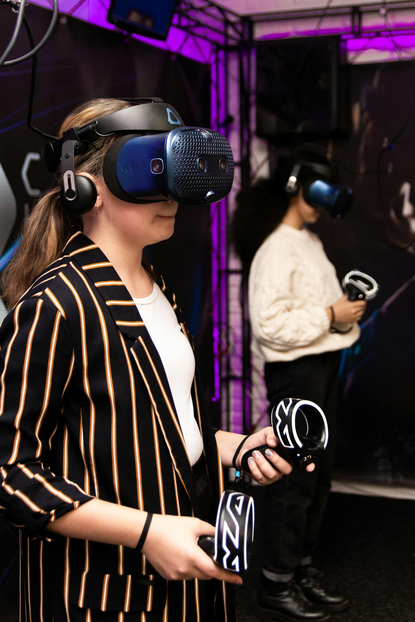 Two women using VR headsets and controllers in an indoor setting.