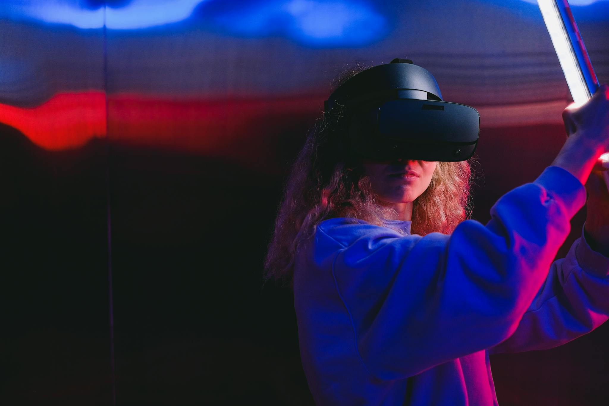 Young woman engaging in virtual reality gaming with a VR headset, colorful lighting.